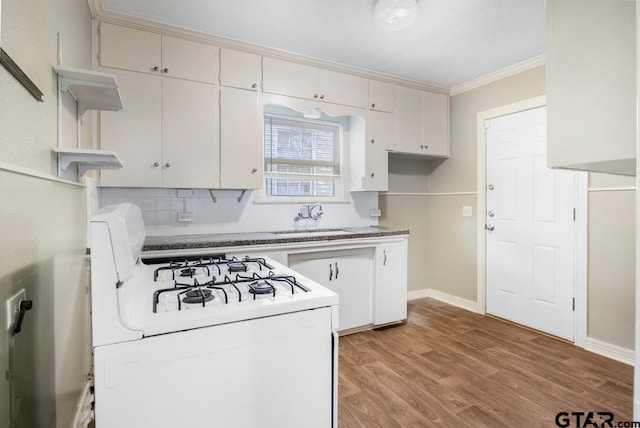 kitchen featuring light wood finished floors, white range with gas cooktop, crown molding, white cabinetry, and a sink