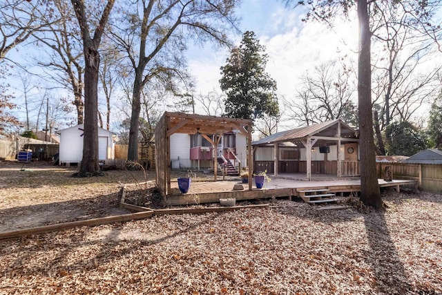 rear view of house with a deck, a gazebo, an outdoor structure, and fence