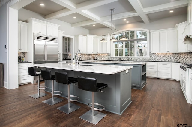 kitchen with dark wood-type flooring, a center island with sink, and decorative backsplash