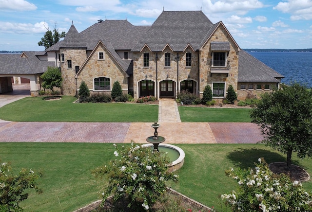 french provincial home with a front yard and a water view