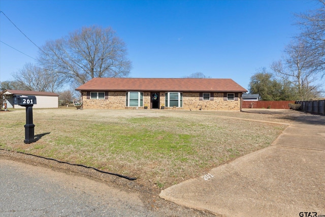 single story home with brick siding, roof with shingles, a front yard, and fence