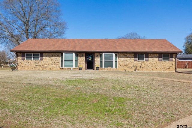 single story home featuring brick siding, a front lawn, and a shingled roof