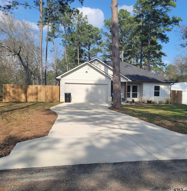 view of front facade featuring a garage, a shingled roof, fence, driveway, and a front yard