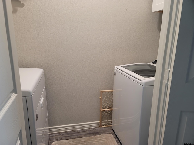 clothes washing area with dark wood-type flooring and separate washer and dryer