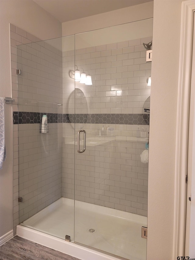 bathroom with a shower stall and wood finished floors