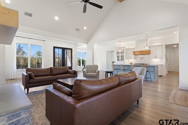 living room featuring ceiling fan, high vaulted ceiling, and light hardwood / wood-style flooring