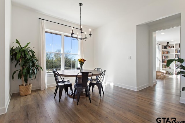 dining space with dark wood-type flooring and an inviting chandelier