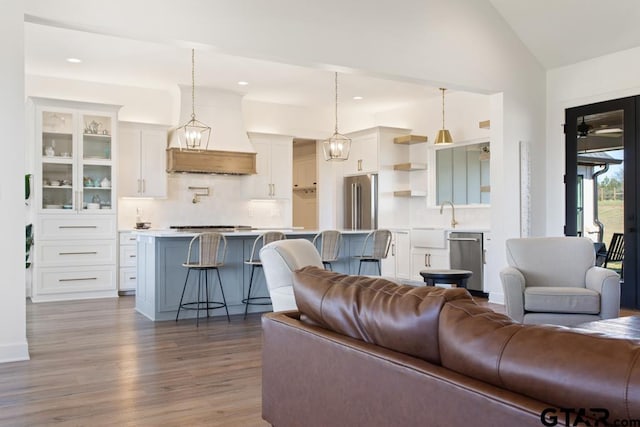 living room featuring wood-type flooring, lofted ceiling, and sink