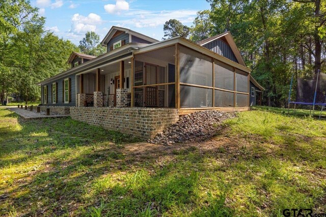 6841 Fm 778, Hawkins, TX 75765 - view of side of property featuring a yard, a trampoline, and a sunroom