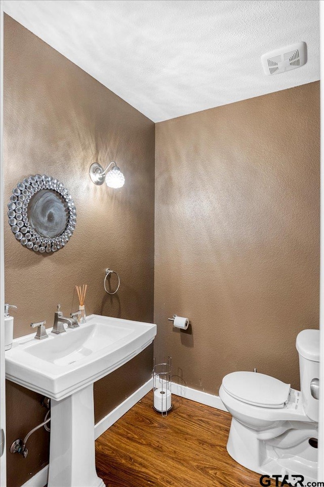 6841 Fm 778, Hawkins, TX 75765 - half bath with baseboards, toilet, visible vents, a sink, and wood finished floors