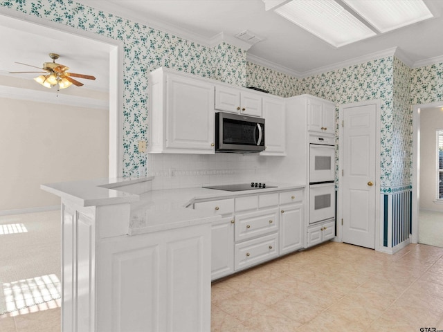 kitchen with crown molding, kitchen peninsula, double oven, and white cabinets