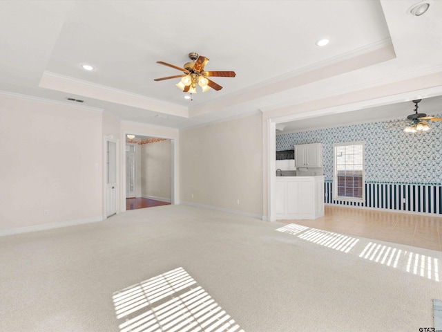 unfurnished living room featuring carpet flooring and a raised ceiling