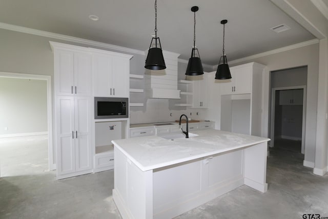 kitchen with white cabinets, light stone countertops, a center island with sink, and ornamental molding