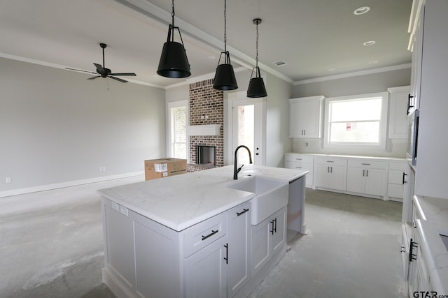 kitchen featuring white cabinetry, sink, light stone countertops, ceiling fan, and an island with sink