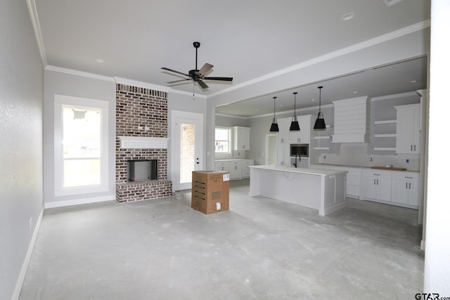 kitchen with an island with sink, hanging light fixtures, white cabinetry, and plenty of natural light