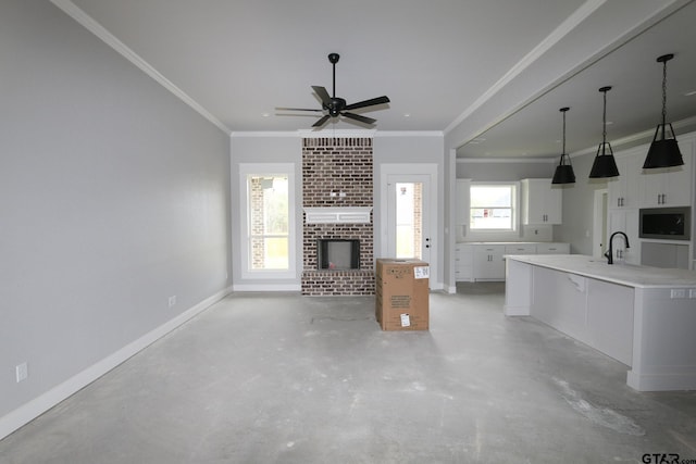 unfurnished living room featuring a fireplace, ceiling fan, sink, and ornamental molding