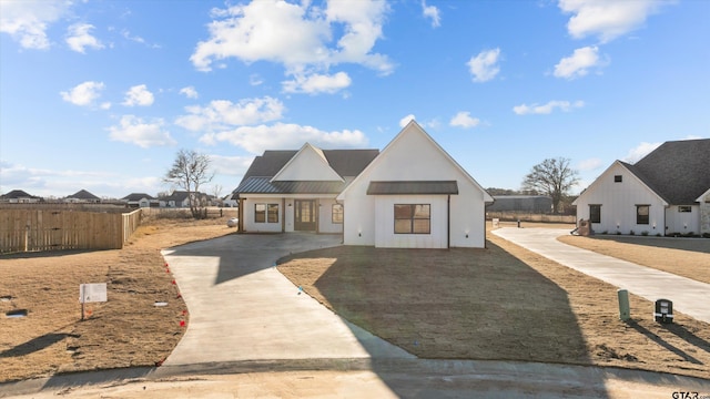 modern inspired farmhouse featuring a standing seam roof, metal roof, and fence