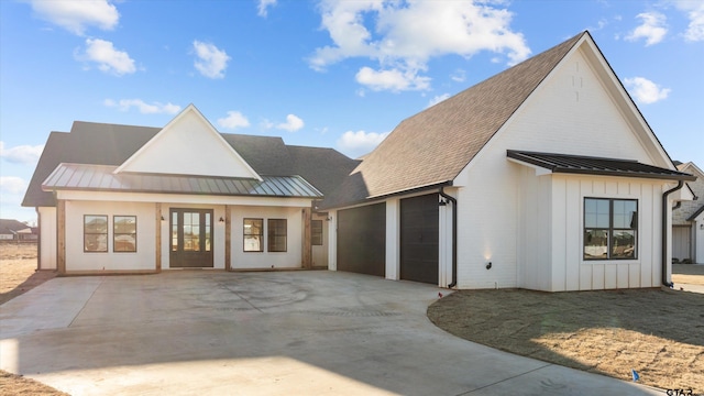 modern farmhouse with a shingled roof, board and batten siding, a standing seam roof, metal roof, and a garage