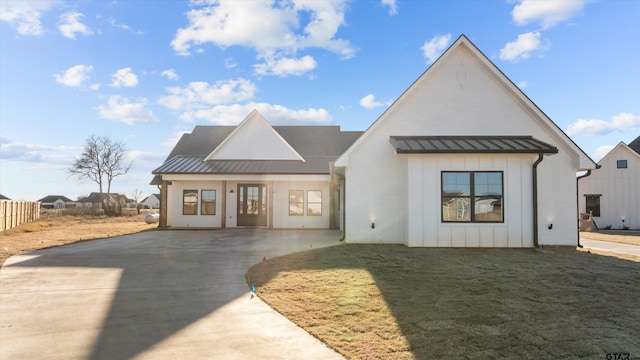 modern farmhouse style home with a standing seam roof, metal roof, and board and batten siding