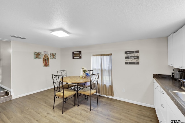 dining area featuring a textured ceiling, light hardwood / wood-style flooring, and sink