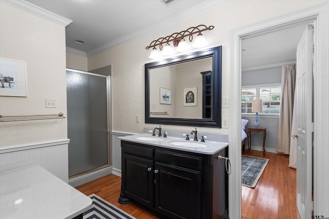 bathroom featuring vanity, wood-type flooring, ornamental molding, and walk in shower