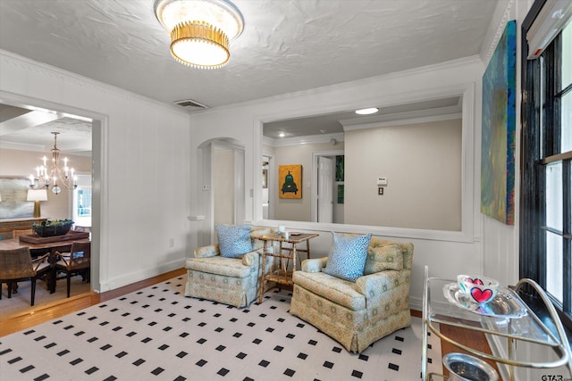 living area with a notable chandelier, wood-type flooring, and crown molding