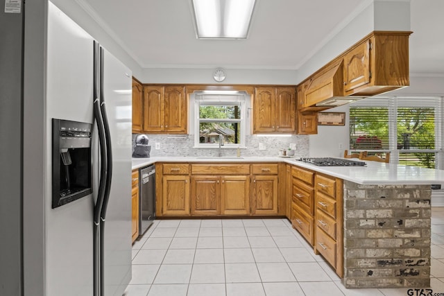 kitchen featuring light countertops, backsplash, a sink, a peninsula, and appliances with stainless steel finishes