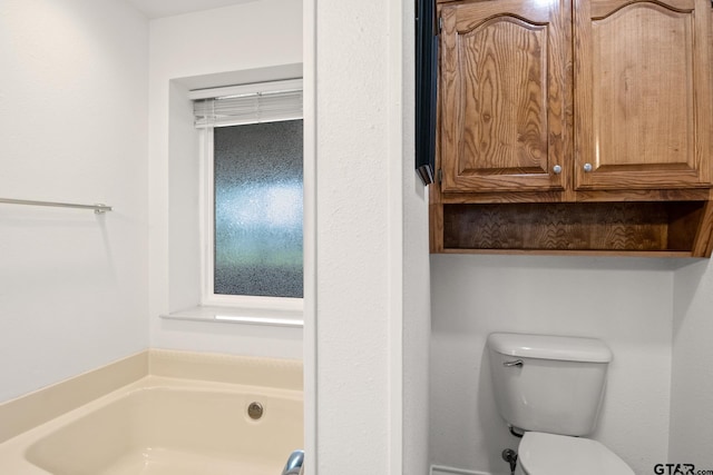 bathroom featuring a garden tub and toilet