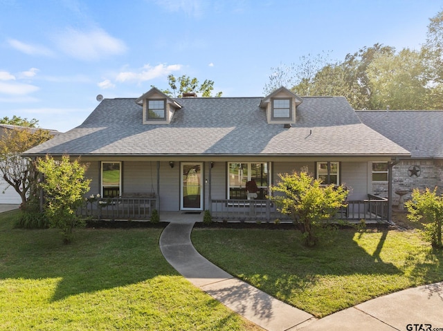 farmhouse-style home with a front yard, a shingled roof, and covered porch