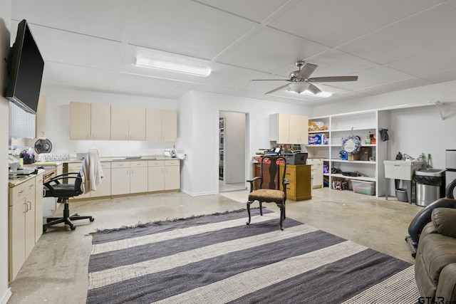 office with a paneled ceiling, concrete floors, and ceiling fan