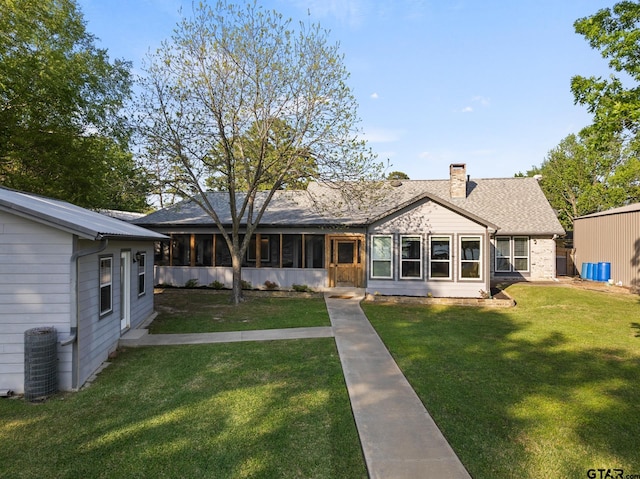 view of front of home with central air condition unit, roof with shingles, a chimney, and a front yard