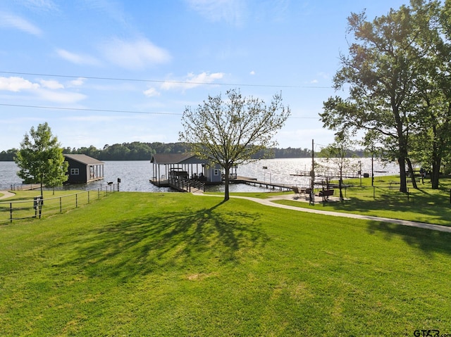 view of yard with a dock, a water view, and fence