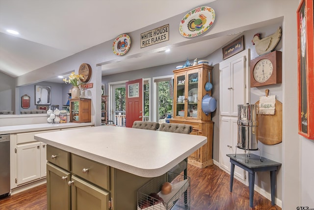 kitchen featuring white cabinetry, green cabinets, dark hardwood / wood-style floors, a kitchen breakfast bar, and a center island