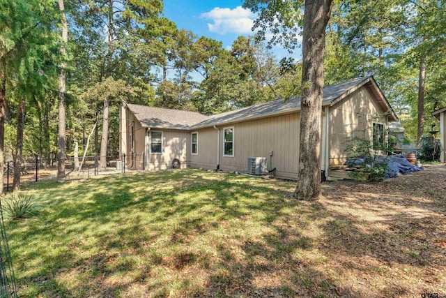 rear view of property with central AC unit and a lawn