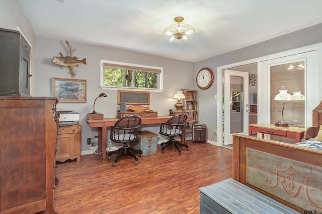 office area with dark wood-type flooring and an inviting chandelier