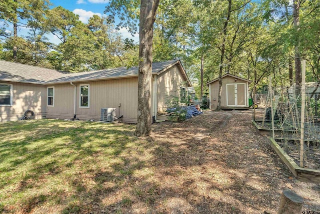 exterior space with central air condition unit, a yard, and a storage unit