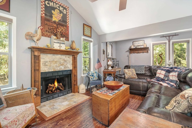 living room with dark wood-type flooring, vaulted ceiling, and a tile fireplace