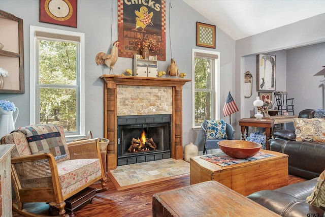 living room with wood-type flooring, a tile fireplace, and vaulted ceiling