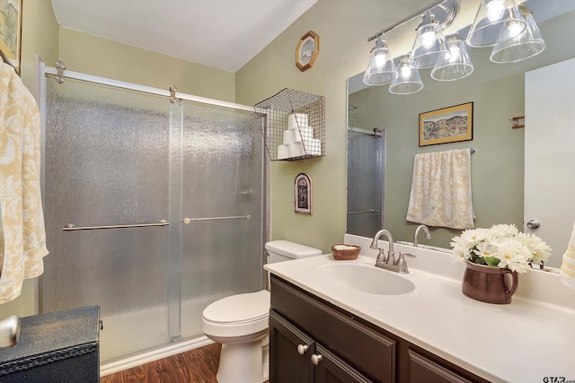 bathroom featuring wood-type flooring, vanity, toilet, and an enclosed shower