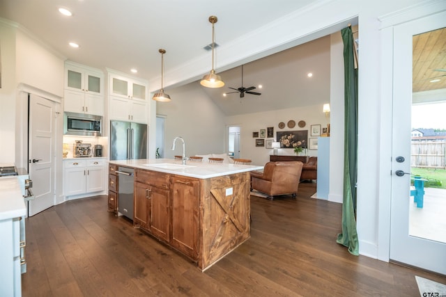 kitchen featuring a kitchen island with sink, sink, decorative light fixtures, white cabinetry, and stainless steel appliances