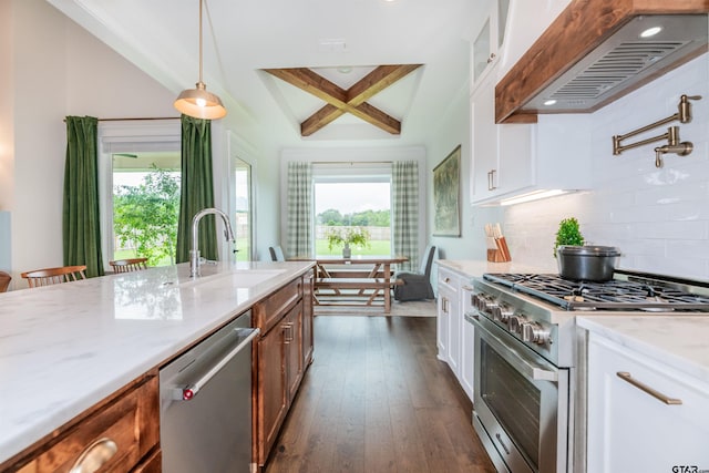 kitchen featuring beamed ceiling, pendant lighting, white cabinets, custom range hood, and appliances with stainless steel finishes