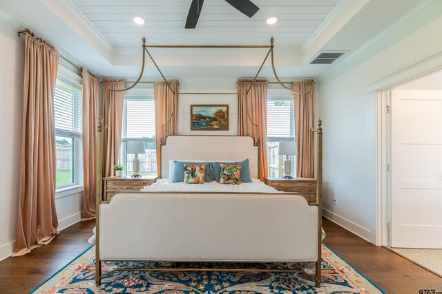 bedroom featuring a raised ceiling, ceiling fan, dark wood-type flooring, and crown molding