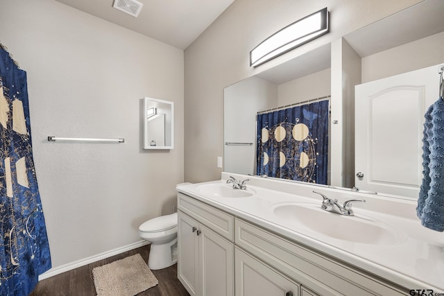 bathroom with toilet, vanity, and wood-type flooring