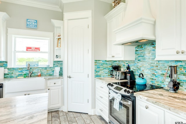 kitchen featuring sink, crown molding, stainless steel electric range, custom range hood, and white cabinets