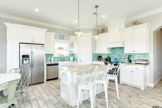 kitchen with white cabinetry, stainless steel appliances, light stone counters, a kitchen island, and custom exhaust hood