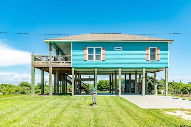 rear view of property with a carport, a deck, and a lawn