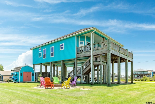 rear view of house with a storage shed, an outdoor fire pit, a yard, and a deck