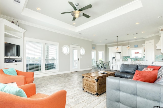 living room with a raised ceiling, ornamental molding, ceiling fan, and light hardwood / wood-style floors