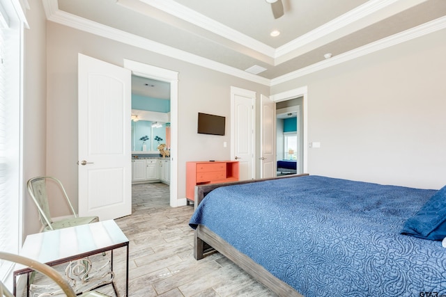 bedroom featuring ceiling fan, a tray ceiling, crown molding, ensuite bath, and light hardwood / wood-style flooring