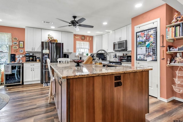 kitchen with dark wood finished floors, white cabinets, beverage cooler, and appliances with stainless steel finishes